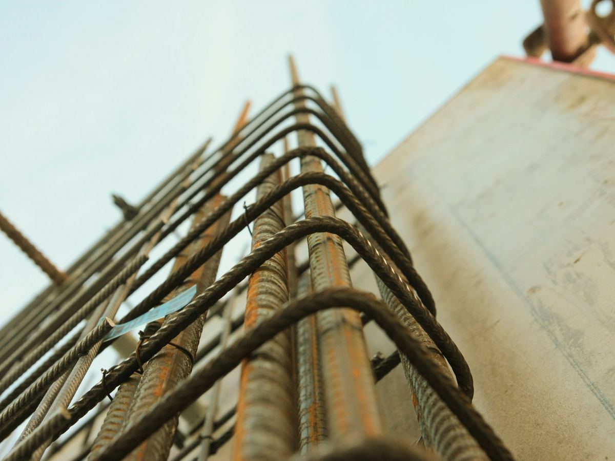 Gebogen wapeningsstaven die uit een betonwand steken, klaar om door te koppelen
